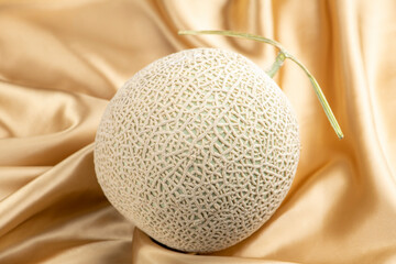 シャンパンゴールドのシルク生地の背景にアールスメロン