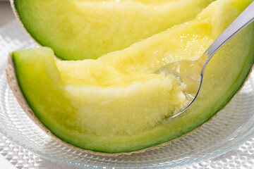 カットしたアールスメロンをスプーンで掬って食べる