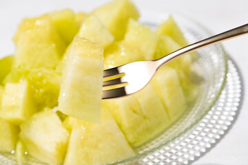 カットしたアールスメロンをフォークで食べる