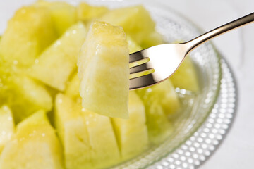 カットしたアールスメロンをフォークで食べる