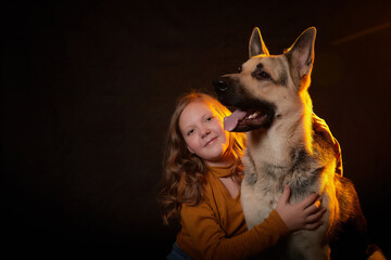Small young girl with german shepherds in front of black background. Model posing in studio