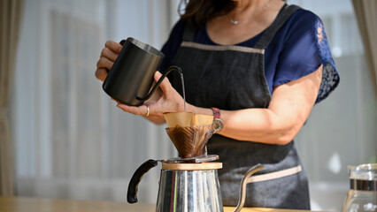 Cropped image, Asian aged or retired woman brewing a morning coffee