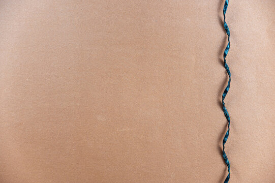 Black spiral cord opposite the brown background. A thin black rope hangs vertically. Minimalist background with copy space for text and design elements