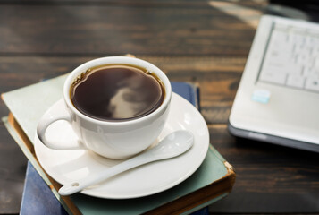 A white coffee cup is placed on the desk. office or at home with a notebook computer keyboard tablet pc