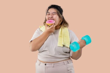 Asian large girl doing fitness exercises with dumbbells and eating sweet donut together isolated.
