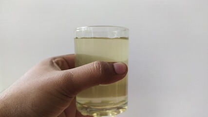 Hand holding glass with brown contaminated undrinkable dirty drinking water on a white background...