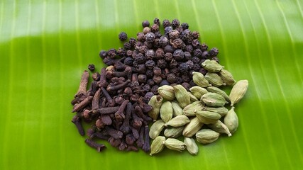 Bunch of organic farm fresh kerala spices cloves, cardamom and black pepper seeds stacked together...