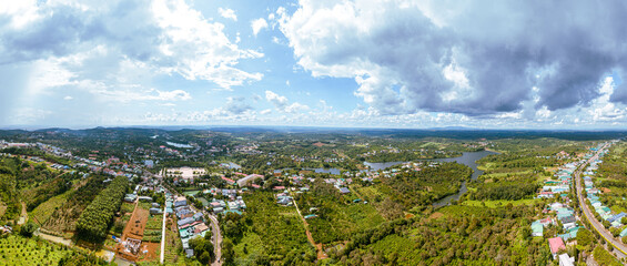 Aerial panorama view of National Route 14 in Kien Duc town, Dac Nong province, Vietnam with hilly landscape, sparse population around the roads and Dak R'tang lake.