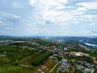 Fototapeta na wymiar Aerial view of National Route 14 in Kien Duc town, Dac Nong province, Vietnam with hilly landscape and sparse population around the roads.