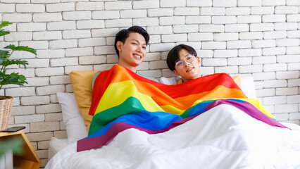 Two Asian young lovely pride male gay men lover couple partner smiling laying down together in bed...