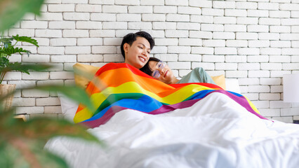 Two Asian young lovely pride male gay men lover couple partner smiling laying down together in bed...