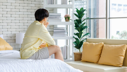 Closeup shot of Asian young upset unhappy thoughtful teenager gay man boyfriend sitting alone on bed having problem trouble and serious thinking after conflict argument fighting with lover couple