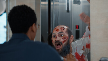 Confident man encountering evil zombies at elevator when leaving work. Horror looking undead...