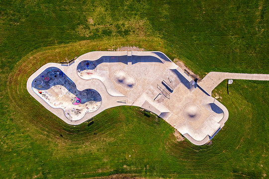 A White Concrete Skate Park Surrounded Grass Viewed From Above