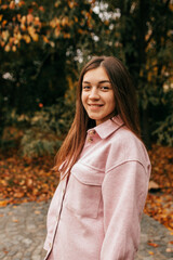 Autumn portrait of young attractive woman who smiles happily on walking walk on warm autumn day in flying park. Indian summer. Weekend. Walking in fresh air.