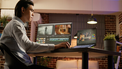 Asian videographer designing video montage on editing software to create movie footage for digital...