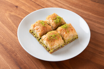 Pistachio baklava in a white plate on wooden background
