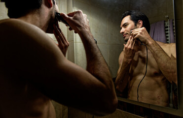 Handsome young male shaving his beard