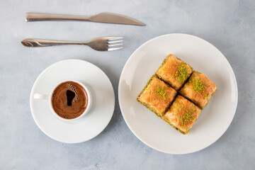Pistachio baklava on a white plate with Turkish coffee.Traditional Turkish baklava and t coffee on a white background