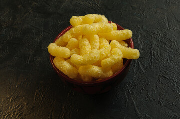 Corn sticks close-up in a bowl on a black background. View from a high angle. Selective focus.