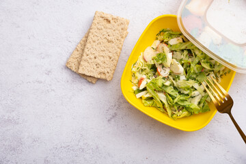 Diet breads and salad of fresh vegetables and crab sticks in a plastic container. The concept of healthy eating