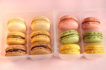 Sweet macaroons in open plastic packages on a pink background. natural light, selective focus