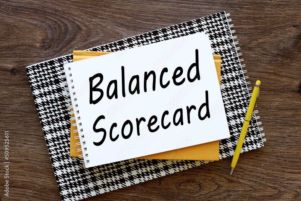 Poster balanced scorecard wooden dark background text on notepad with spiral. three notebooks on the table 