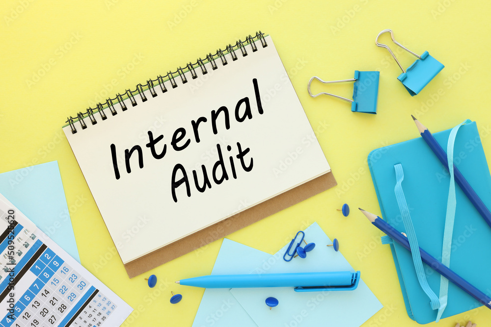 Poster internal audit concept. text in open notepad on yellow background near blue calendar and blue notepa