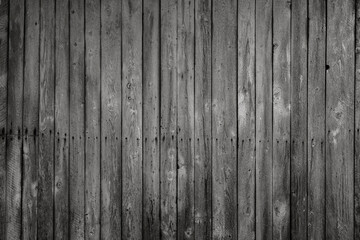 Front view of an old, weathered and dark wooden wall in black and white. Abstract full frame textured background.