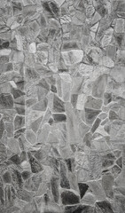 Front view of stone wall made of weathered stone slates. Abstract high resolution full frame textured background in black and white.