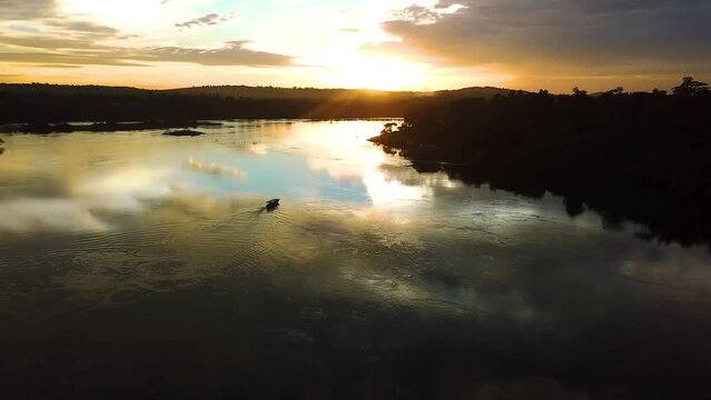 Aerial view of lone boat crusing on Nile River during sunset golden hour, picturesque scenery