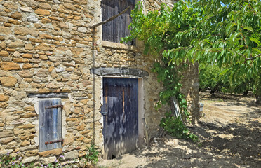Fototapeta na wymiar part of old building with ltrees in an orchard in south of France