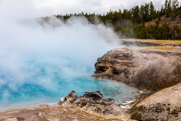 Blue pond with smoke inside dangerous hot zone in Yellowstone.
