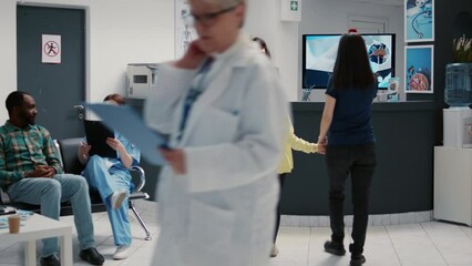 Mother and little girl writing checkup report at hospital reception desk to attend medical appointment. Patients having healthcare examination to receive support and assistance.
