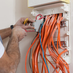 installation of an electrical panel, hands screwing the automatic switch