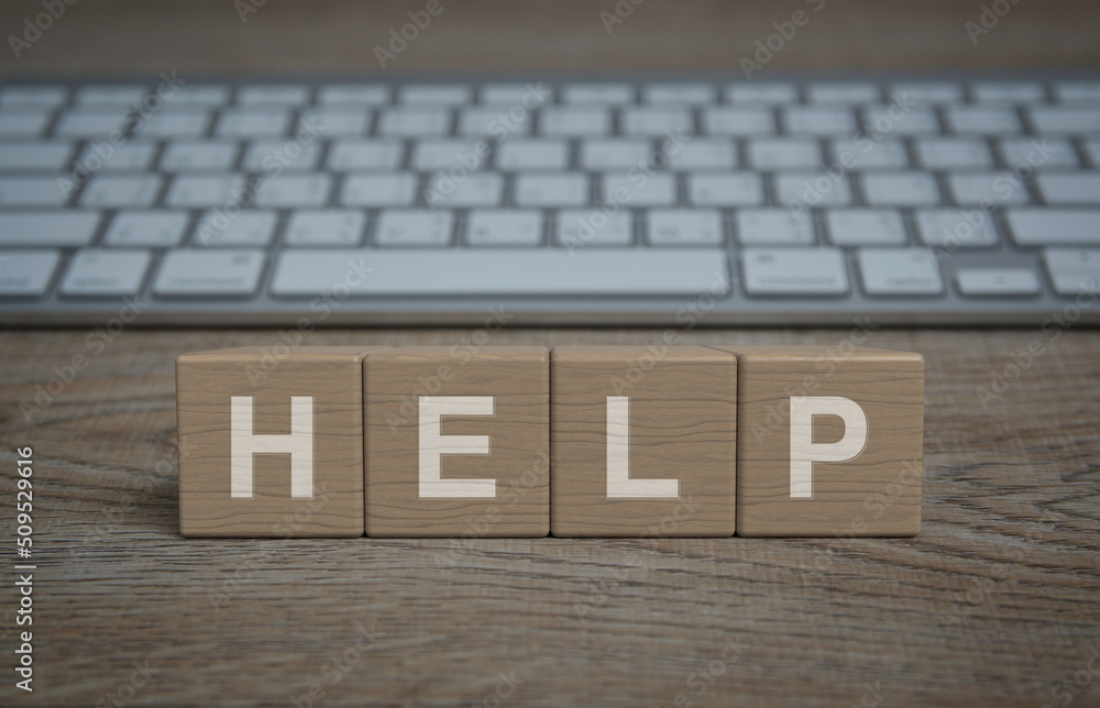 Aufkleber help letter on wood block cubes on wooden table with modern computer keyboard, business customer ser