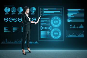 businesswoman with laptop standing on abstract glowing background with business charts and graphs...