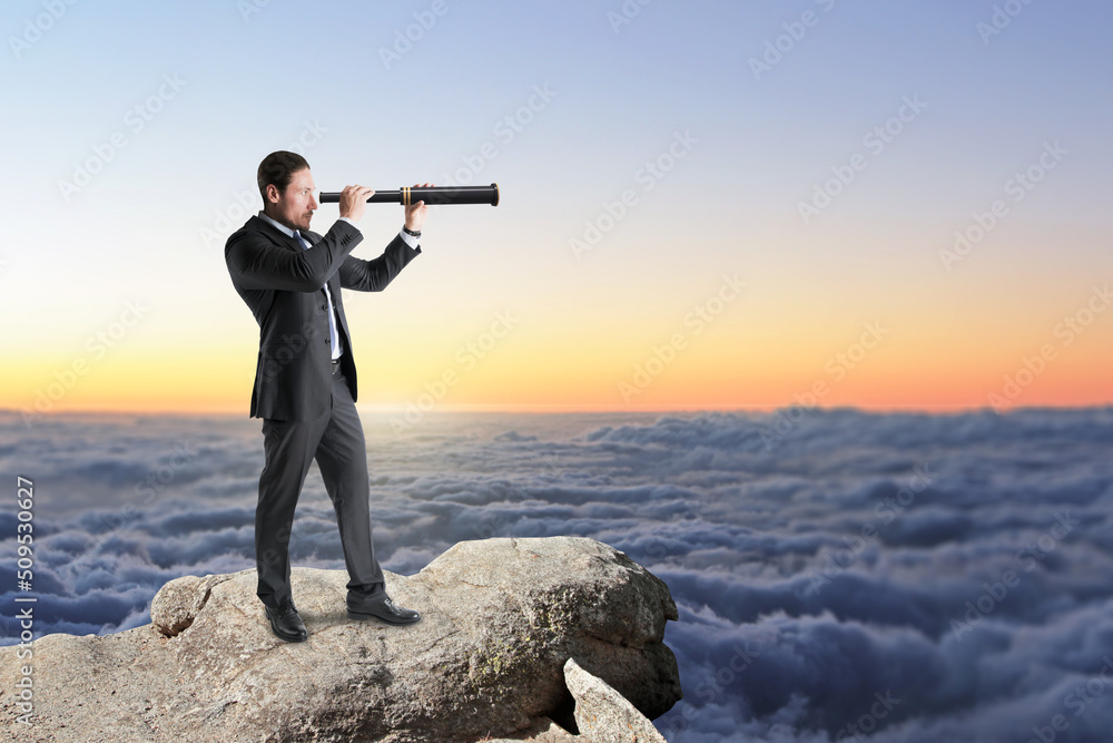 Poster  businessman with telescope standing on cliff and looking into the distance on bright blue sky and clouds background with mock up place for your advertisement. 