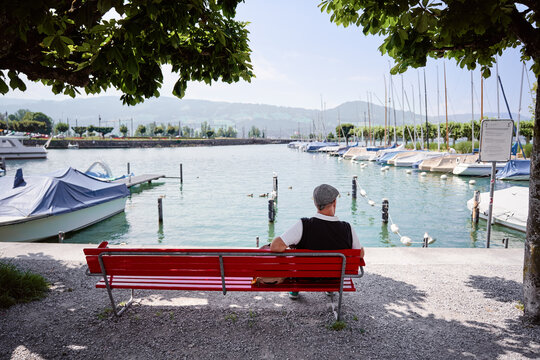 Man siiting on bench enjoying wonderful view of lake.