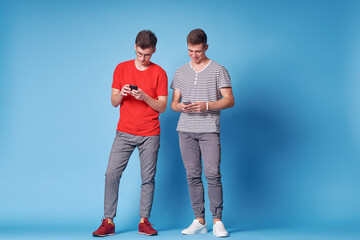 Youth and technology. Young happy friends using smartphone together. Blue background.