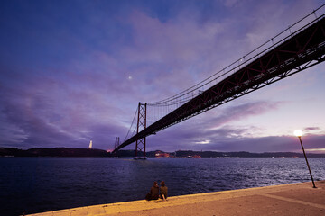 Fototapeta na wymiar Beautiful landscape with suspension 25 April bridge bridge over the Tagus river in Lisbon at night time, Portugal.
