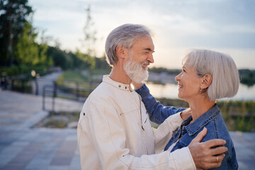 Outdoors portrait of happy elderly couple embracing in summer park.