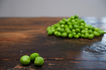 Fresh peeled green pease on a brown wooden table with copy space. Still life of green peas in pods with pea shoots on wooden table