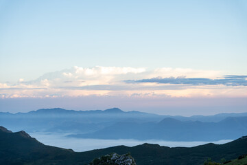 view of the clouds below and above the mountains at sunrise