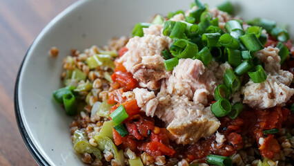 Buckwheat close-up with Tuna fish, tomato sauce, and scallions on a plate.