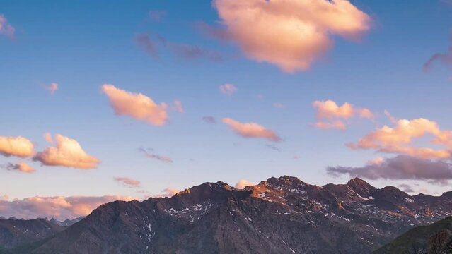 Time lapse, moving clouds in the valley below mountain ridges and peaks of the Alps. Majestic snow capped summit (M. Viso, 3841 m) against clear blue sky. Valle Varaita Piedmont Italy