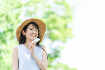 帽子を被って紫外線対策するアジア人女性（笑顔・日焼け止め）
