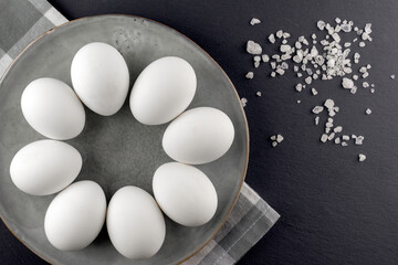 White eggs in a black plate on a black background.Top view.