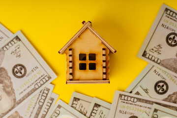 Wooden house with dollars banknotes close-up. Concept of savings, investment in real estate, refinance, retention, collect money for buy, sell, decorate or repair for home