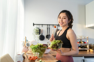 Portrait of Asian attractive woman cooking salad and look at camera. 